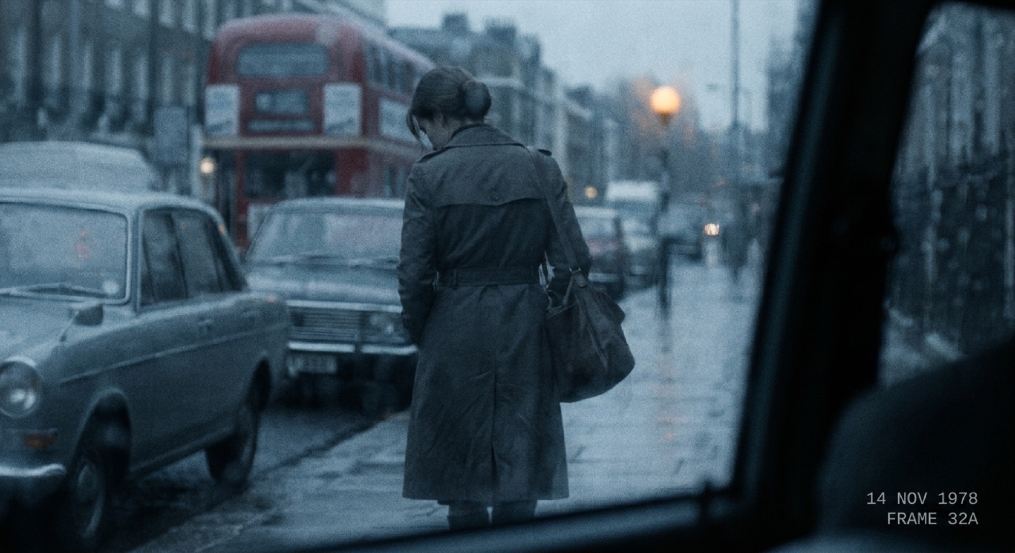 A surveillance photograph: a woman walking, seen from behind, on a wet street at dusk.